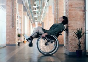 Woman resting in wheelchair against brick wall