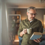 old white guy reading a book and drinking coffee